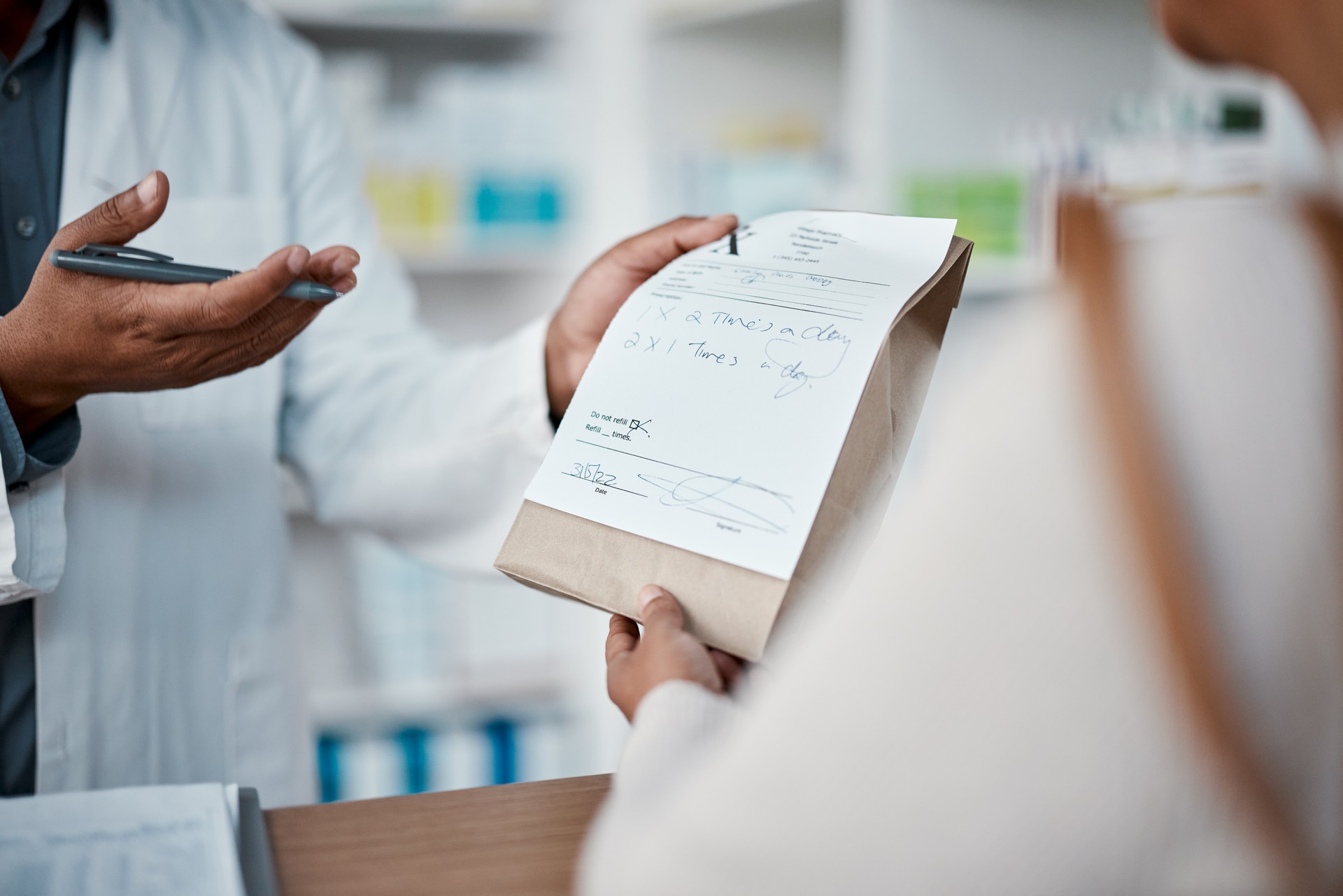 Healthcare, pharmacist hands with medicine for woman at counter buying prescription drugs at drug store. Health, wellness and medical insurance, man and customer at pharmacy for advice and pills.